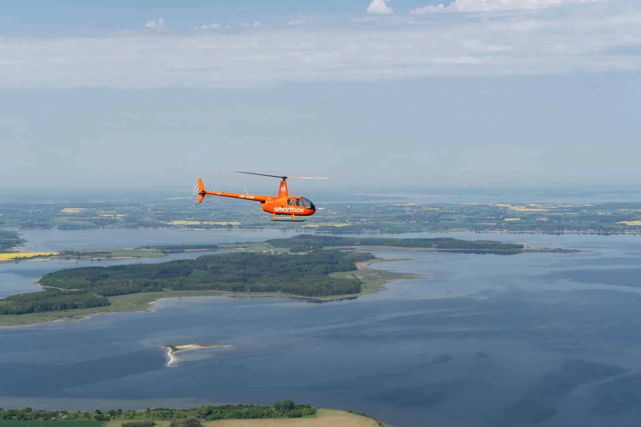 En orange helikopter over en fjord