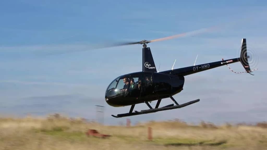En sort helikopter over en eng