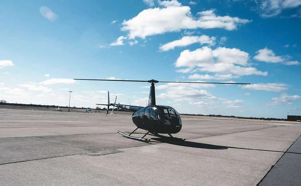 En sort helikopter på forpladsen under blå himmel